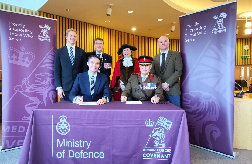 Cllr Tom Gracey signs the Armed Forces Covenant in front of the Mayor and MP